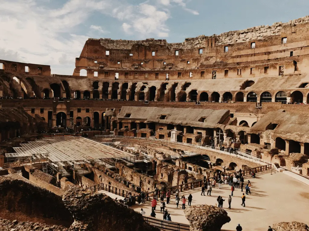 Interior view of the Colosseum in Rome with tourists exploring ancient Roman ruins.