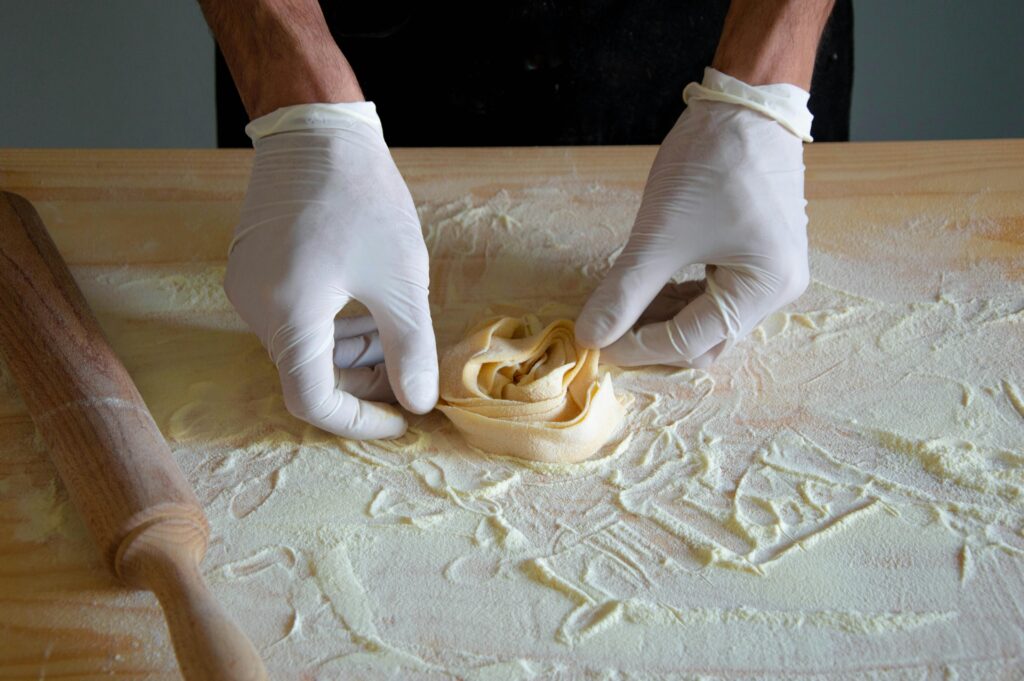 Gloved hands shaping fresh pasta on a floured surface during a traditional Italian cooking class in Rome